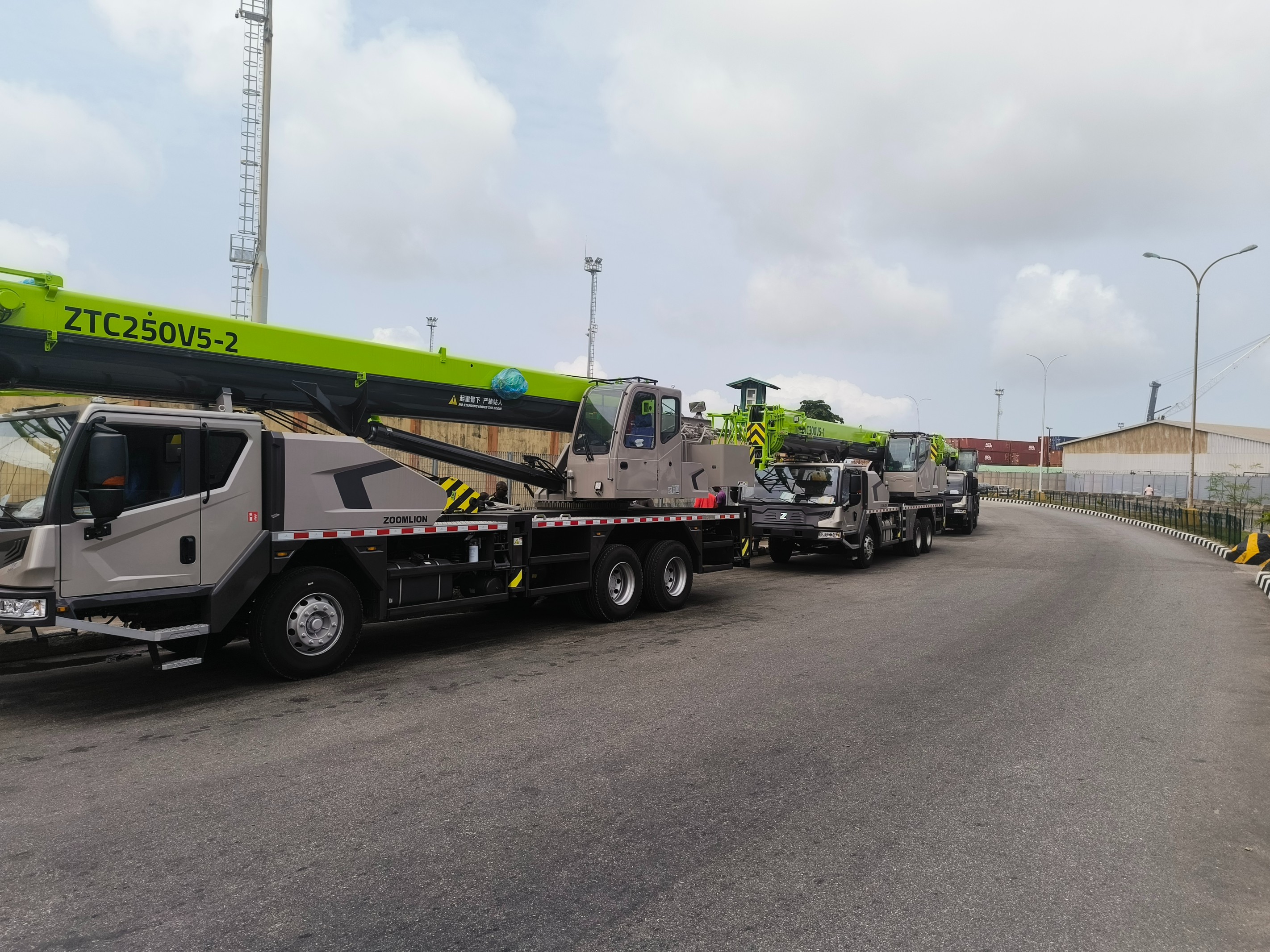 Fleet of Zoomlion mobile crane trucks lined up at a project site